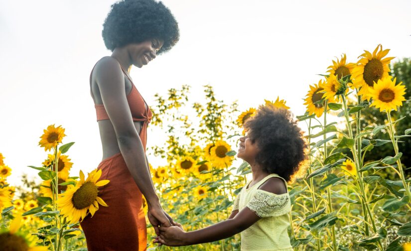 Beautiful mom and daughter in a sunflowers field