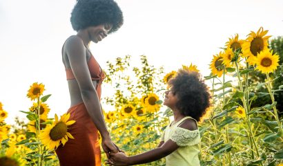Beautiful mom and daughter in a sunflowers field
